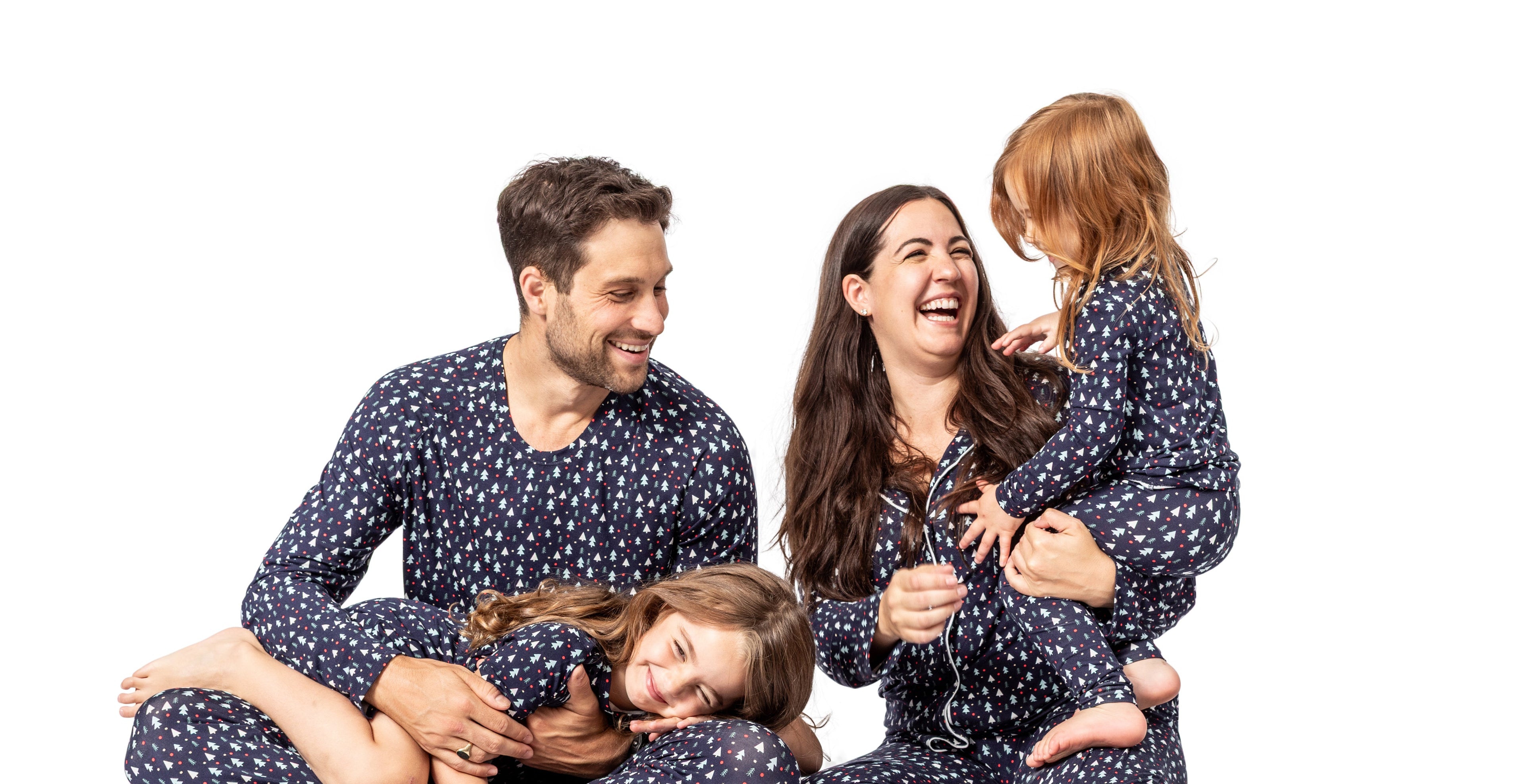Family of four wearing matching navy pajamas with white polka dots on a white background