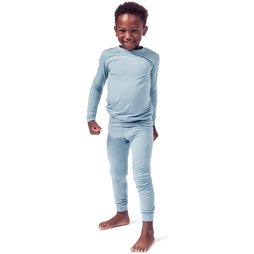 A child standing and posing in a blue bamboo PJ set with elastic waistband and snug cuffs.