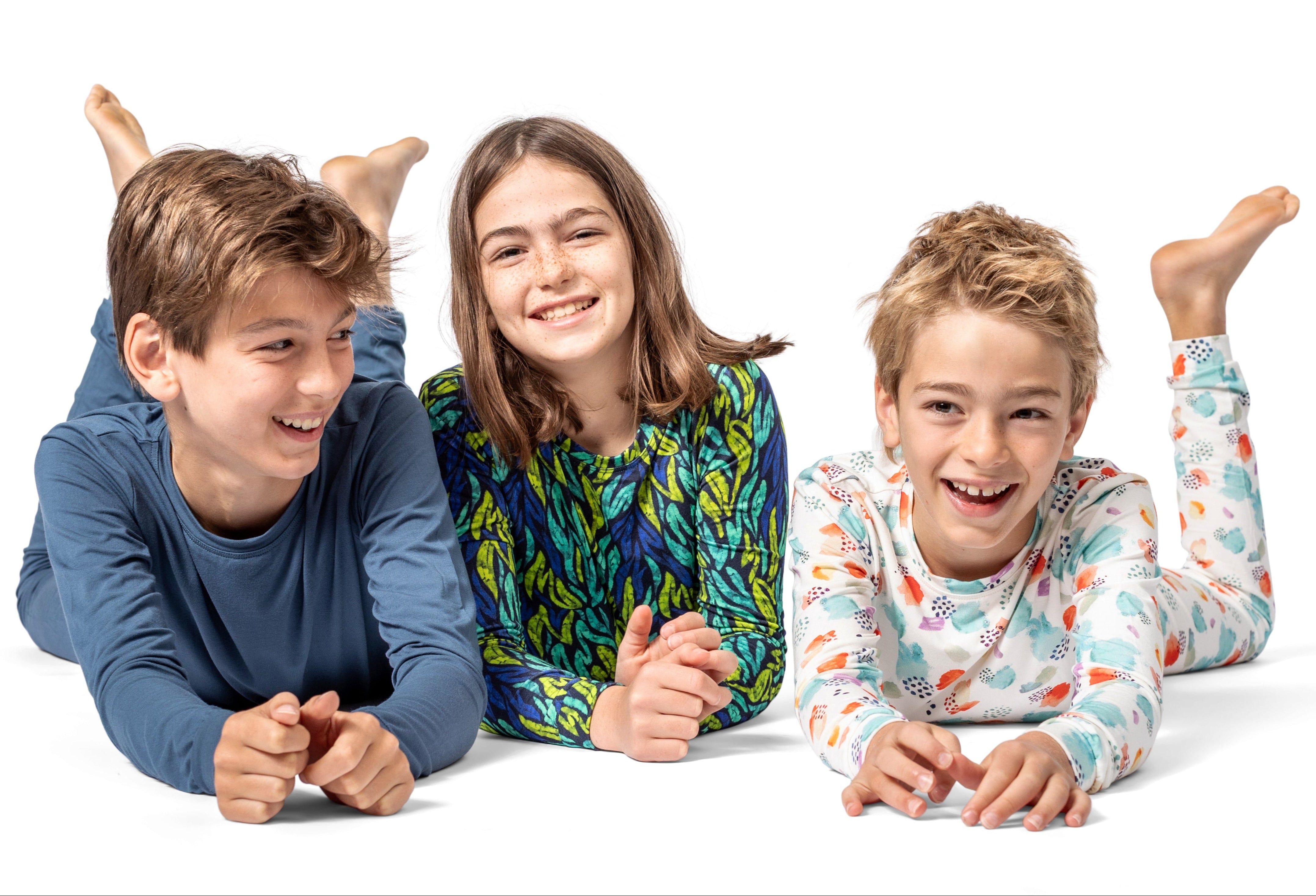 Three children lying on a white background, smiling and posing.