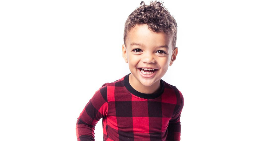 Child wearing red and black checkered pajamas on a white background