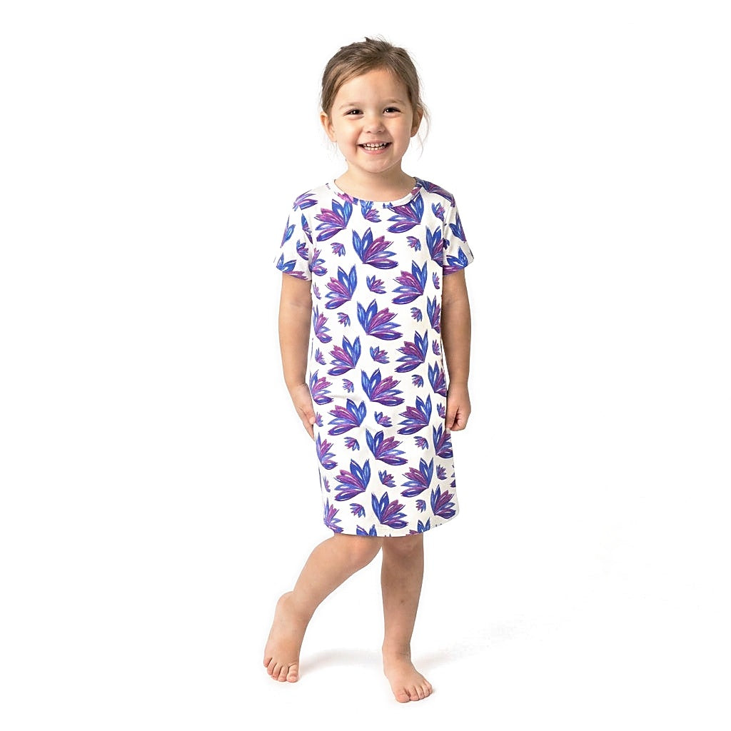 Young girl wearing the Lily Kids Snuggle Dress, a short-sleeve T-shirt dress with blue and purple leaf print, front view