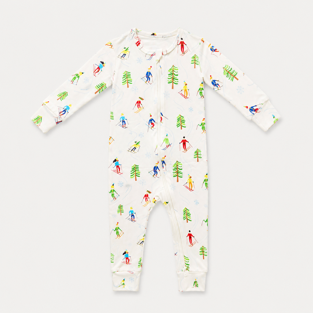 A baby long-sleeve footless one-piece sleeper with a white background and a colorful allover print of skiers and pine trees, shown flat on a light gray background.