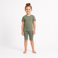 Young girl wearing a green t-shirt and shorts set on a white background